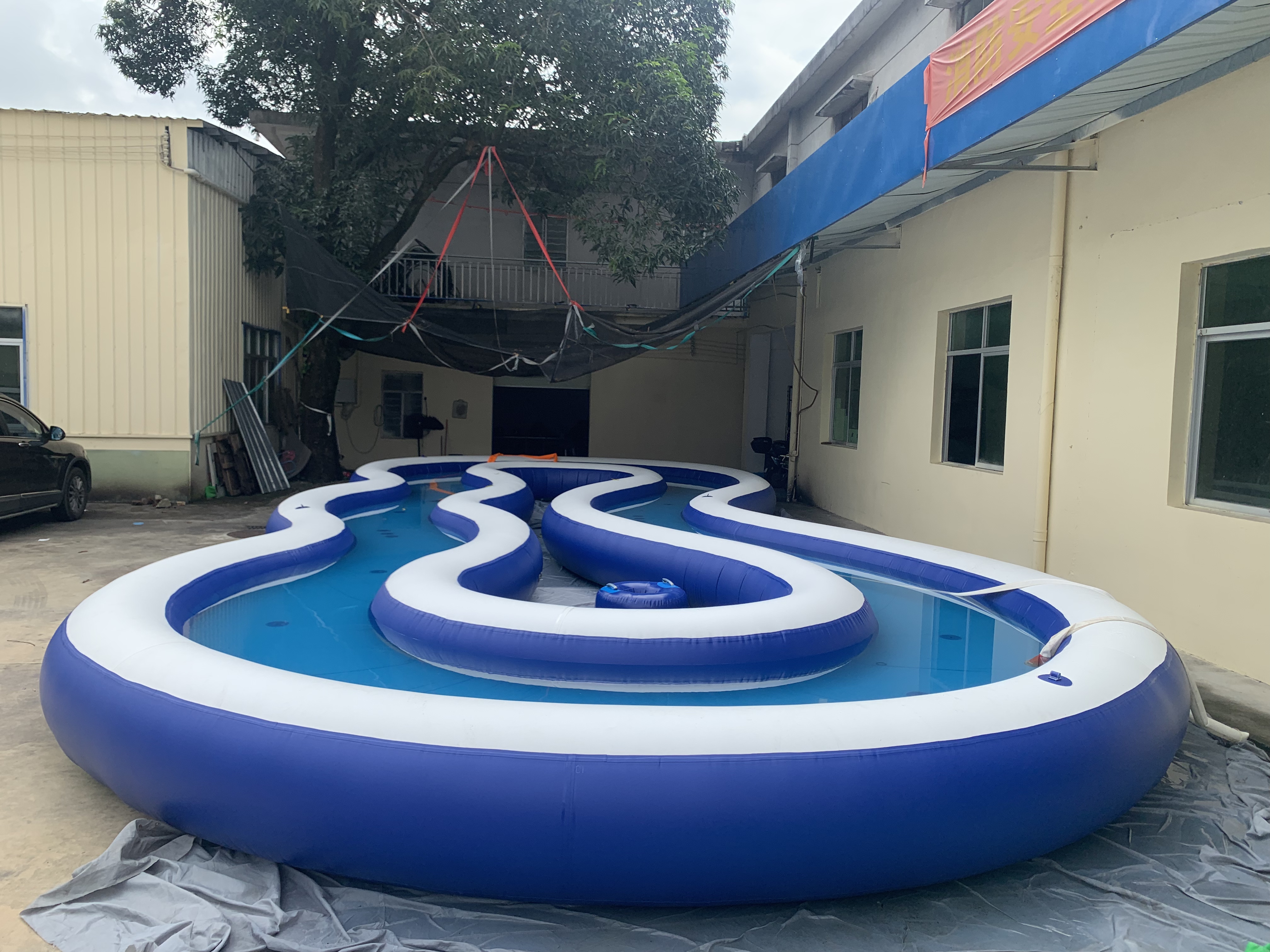 Commercial inflatable lazy river filled with water in an outdoor yard.